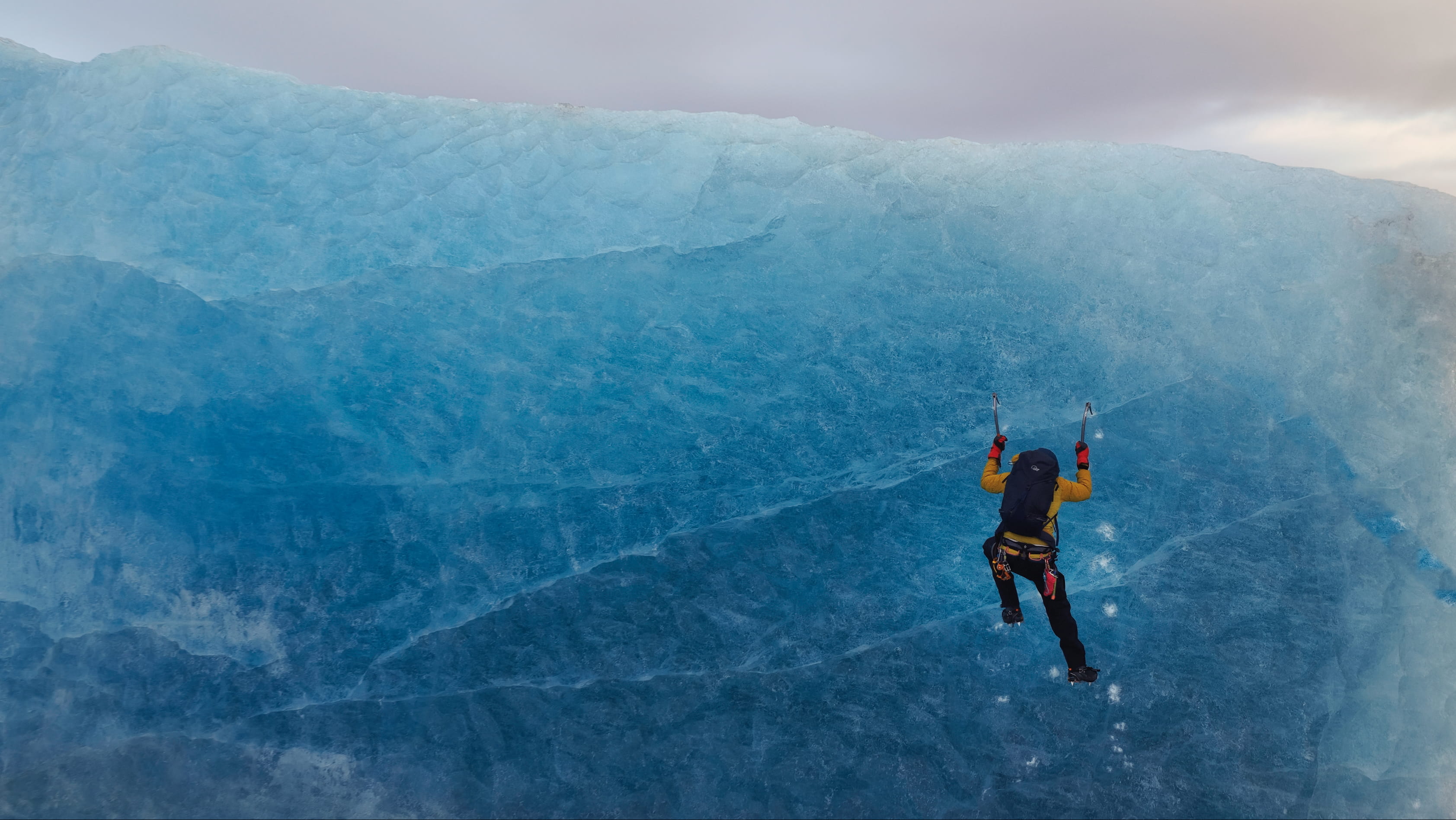 Ice climber scaling a blue glacier wall